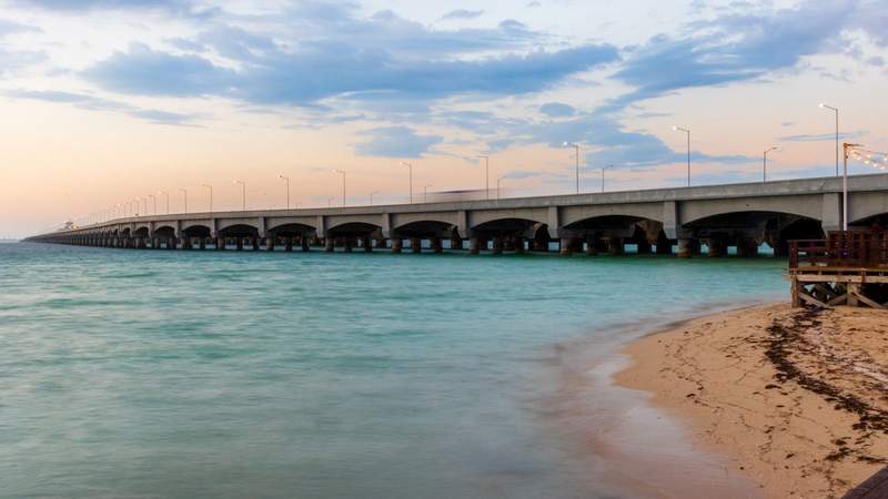 A long industrial pier and the ocean at sunset.