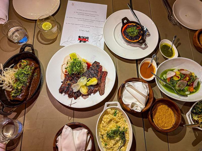 Shareable plates of food on a wooden table at Toro Bravo steakhouse in Reno.
