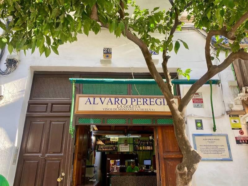 Outside of the bar, with wooden doors and a green awning. 