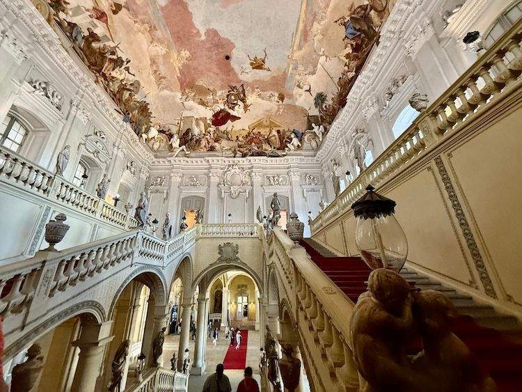 Interior of the Würzburg Residenz showing the grand staircase and expansive Baroque ceiling fresco by Tiepolo.