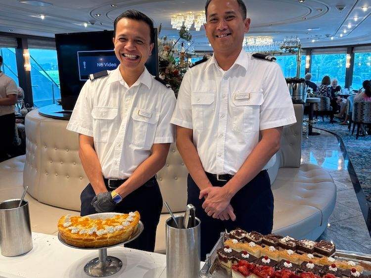 Crew members serving tea and sweets during an onboard High Tea