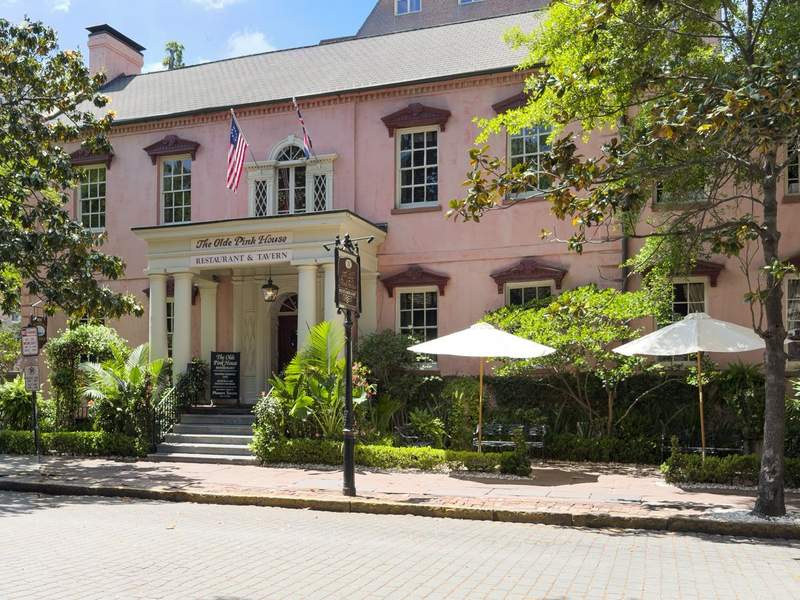 Front entrance of The Olde Pink House restaurant in Savannah, Georgia, featuring its historic pink stucco exterior, classic columns, and inviting steps.
