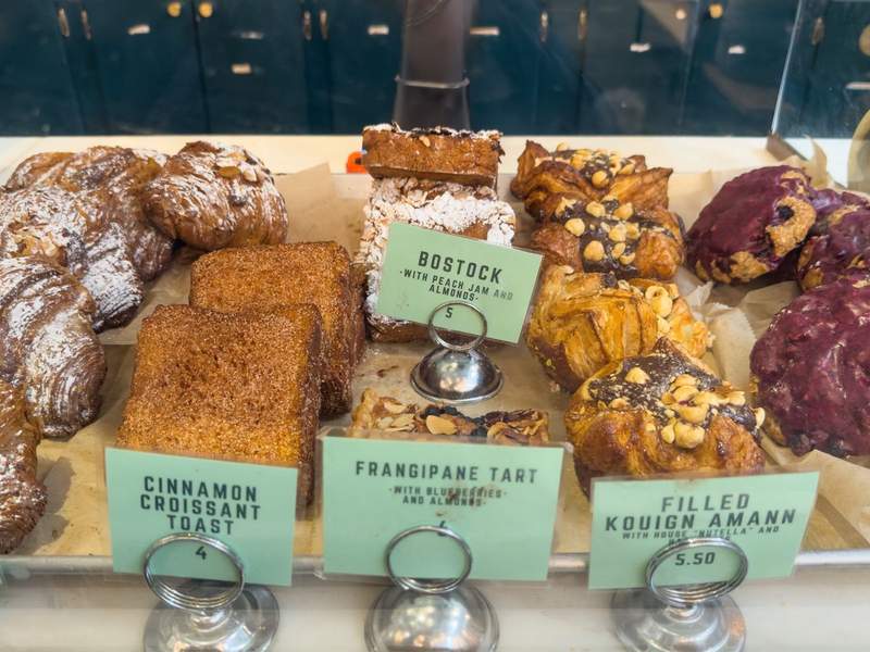 Display of pastries at Little Tart Bakeshop in Atlanta, Georgia, featuring golden croissants, fruit tarts, and baked goods arranged on trays.