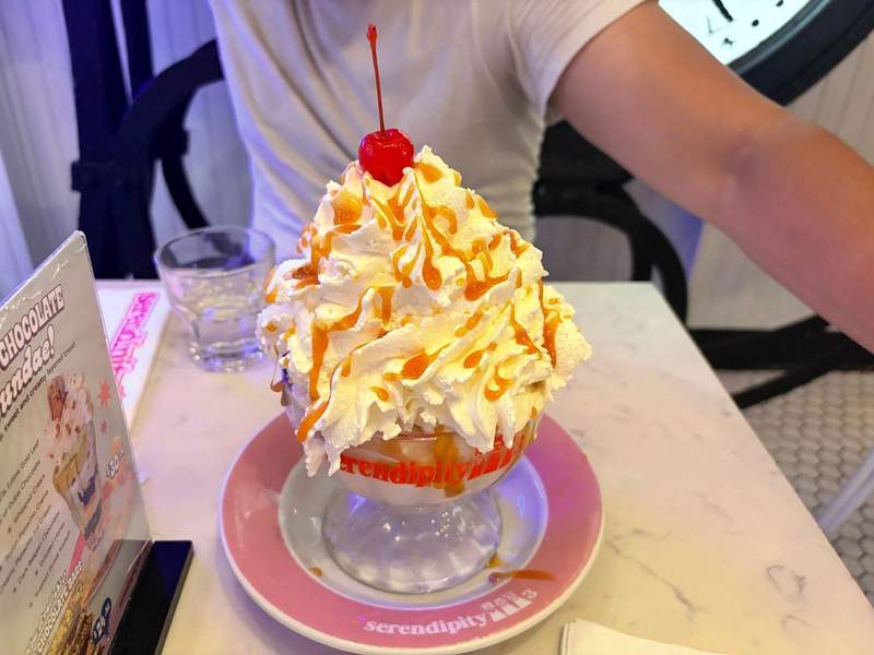 A romance end to date night with a goblet filled with vanilla ice cream and topped with whipped cream and a cherry at Serendipity 3.