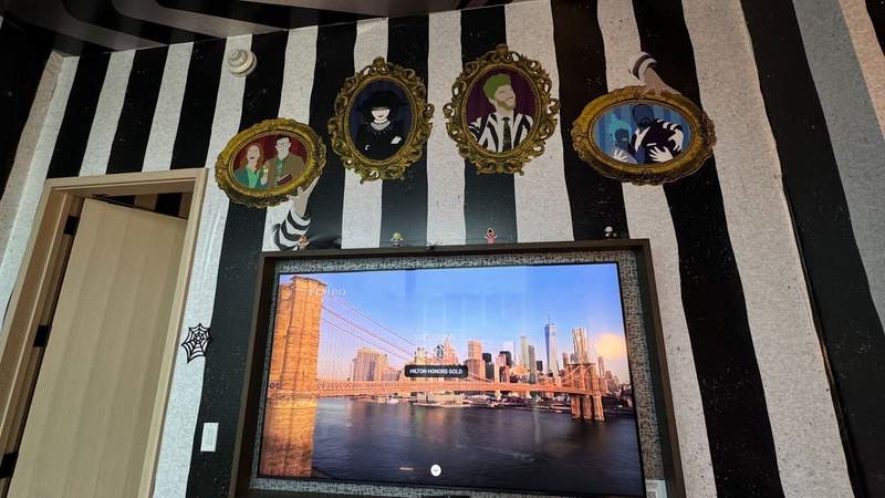 black and white striped wallpaper with character images next to a flat screen television inside the Beetlejuice suite.