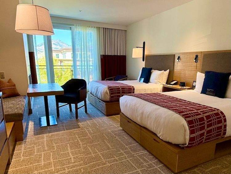 Hotel room at the Limelight featuring two large beds, desk area, and contemporary furnishings with warm, mountain-style design elements.