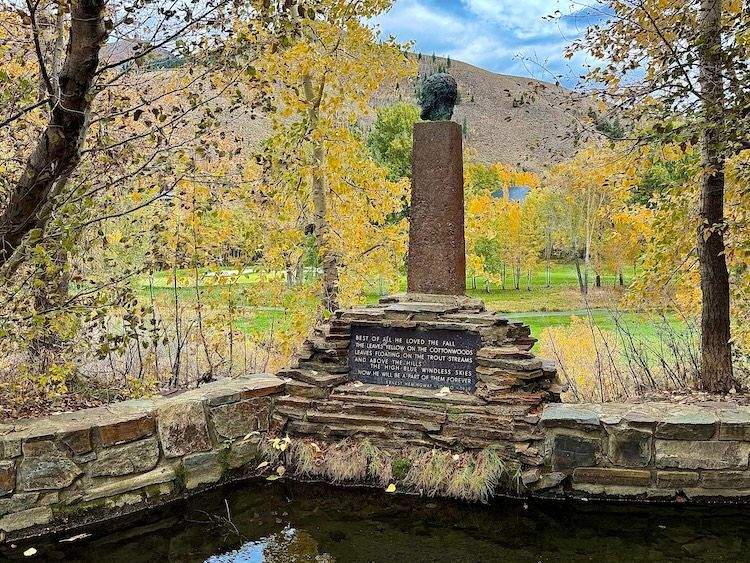 Stone Hemingway Memorial surrounded by fall-colored trees, overlooking Trail Creek in the Idaho mountains.