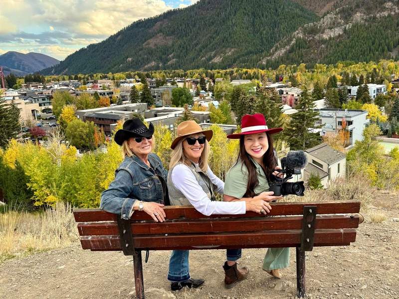Three friends sitting on a bench at Knob Hill overlook in Ketchum, Idaho, enjoying the mountain view during the Trailing of the Sheep Festival.