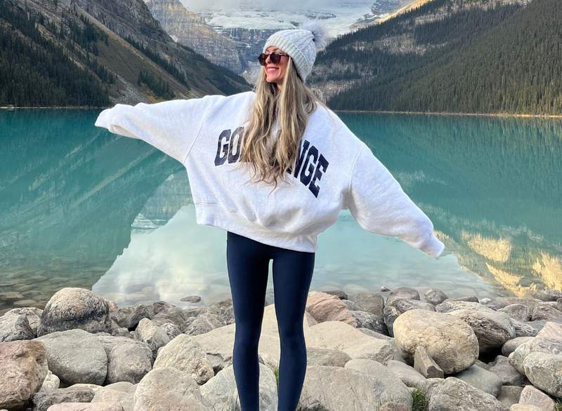 A woman poses on the rocks along the milky-blue waters of Lake Louise.
