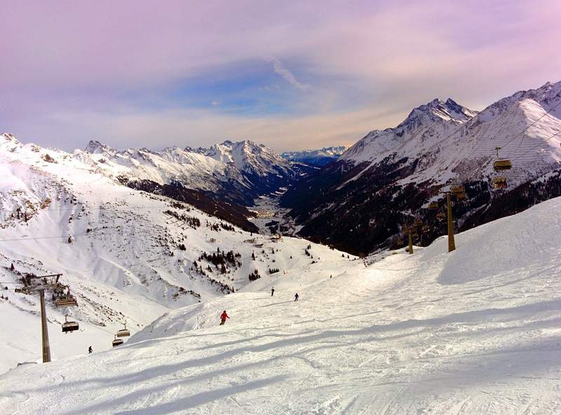 Skiers on the slopes of the Arlberg surrounded by mountains in the Austrian Alps. 