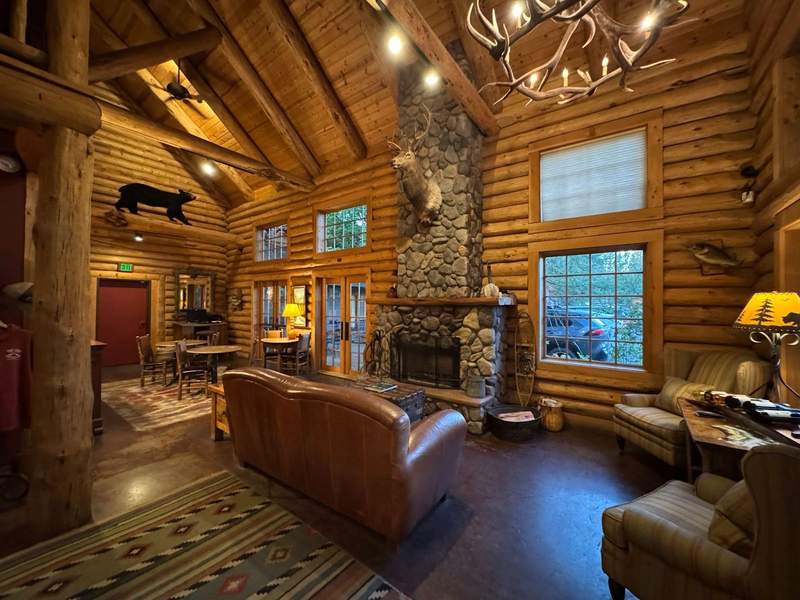 The lobby of the Lodge at Riverside is a log lodge with a stone fireplace and comfy seating. Deer head, a stuffed bear and a mounted fish are some of the decor.