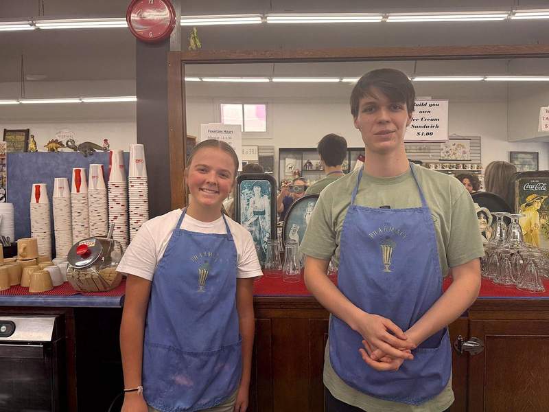 Teenage boy and girl with aprons on serve as soda jerks at the Grants Pass Pharmacy