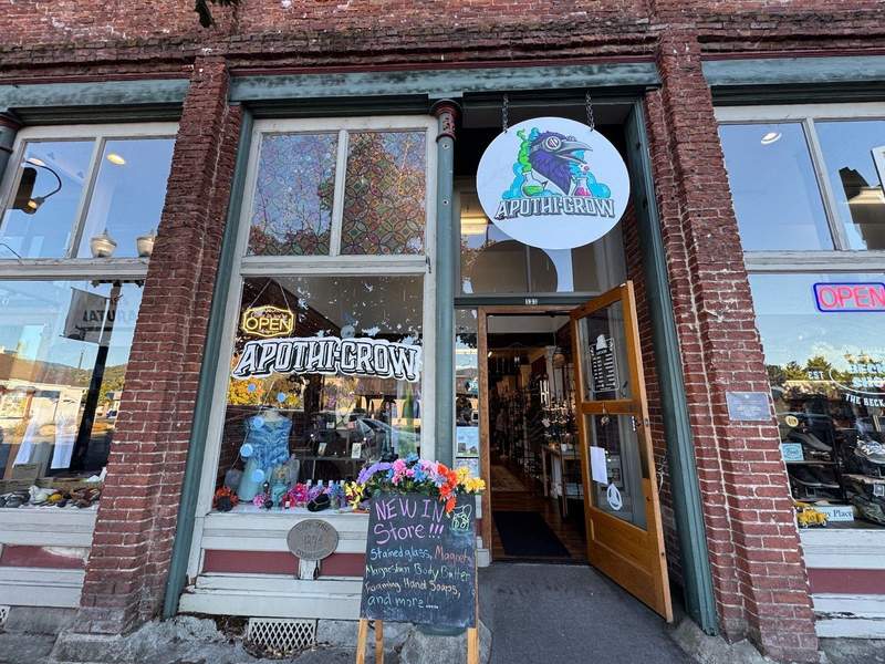 Old brick building housing Apothi-Crow. The brightly colored sign has the logo featuring a crow.