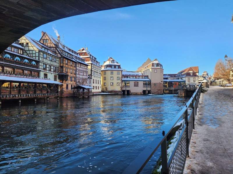 Walking along the riverbank in Colmar with the buildings lightly covered in snow