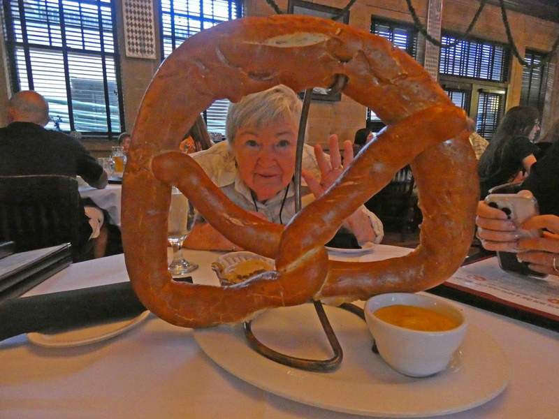 A woman at a table looking through a hugh pretzel.