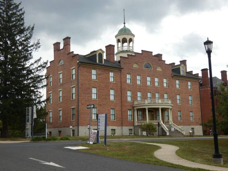 A four story brick building wiht a white cupola on top.