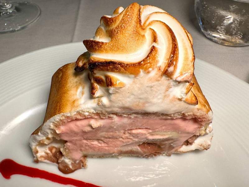 Classic baked Alaska, toasted meringue surrounds melted Neapolitan ice cream and cake. 
