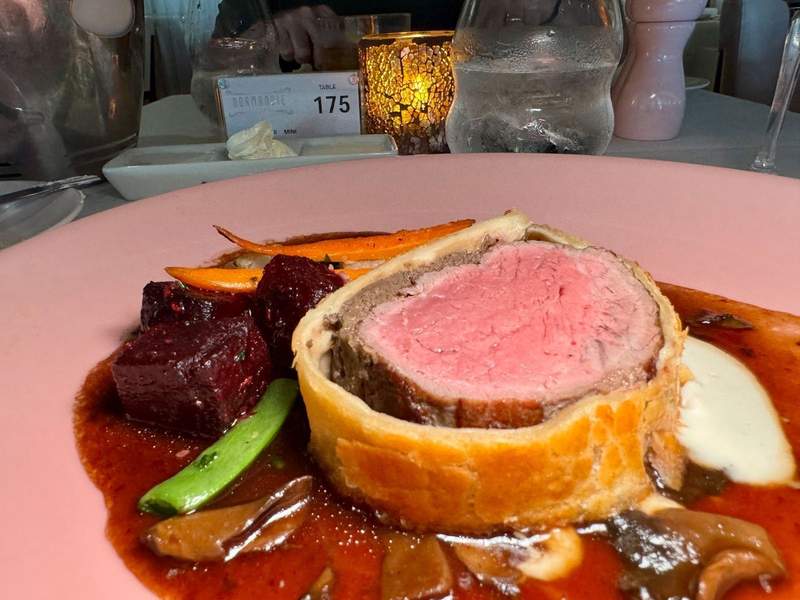 Beef Wellington, beef wrapped in a pastry crust with sauces, red beets, carrots, and mushrooms.