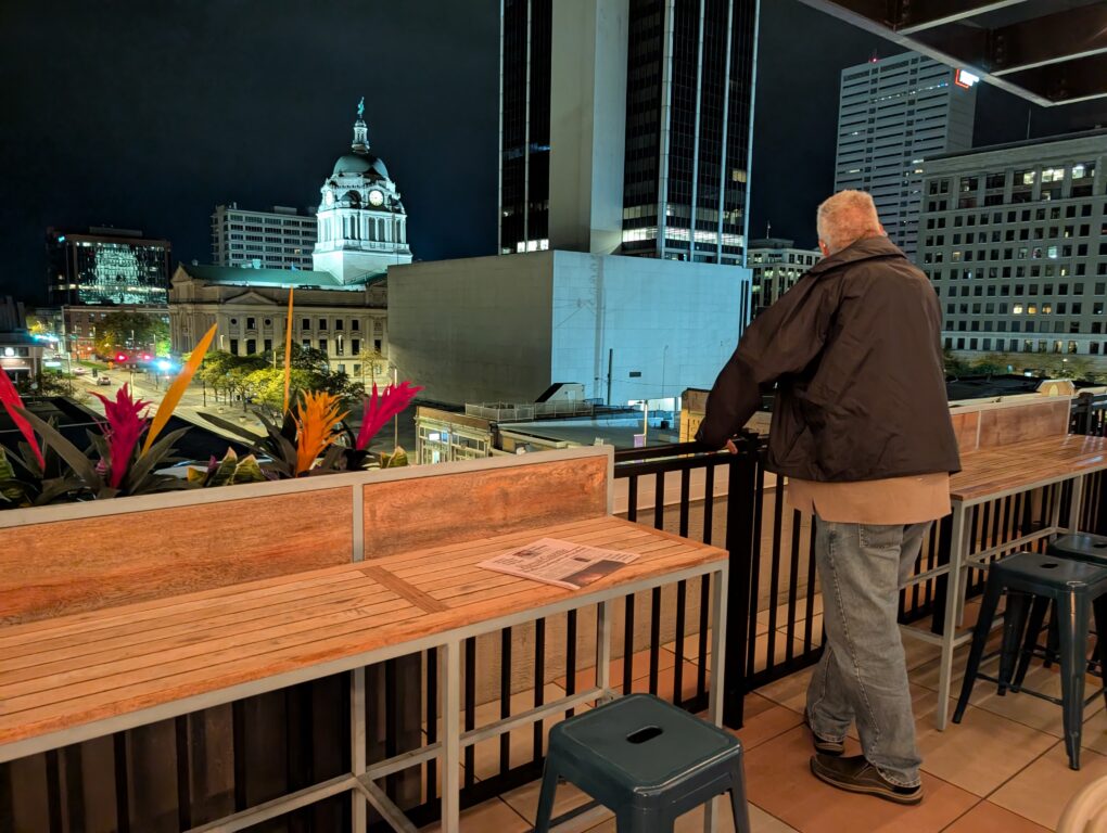 Man looking at the view of downtown Fort Wayne from Birdie's Rooftop Bar at The Bradley Hotel.
