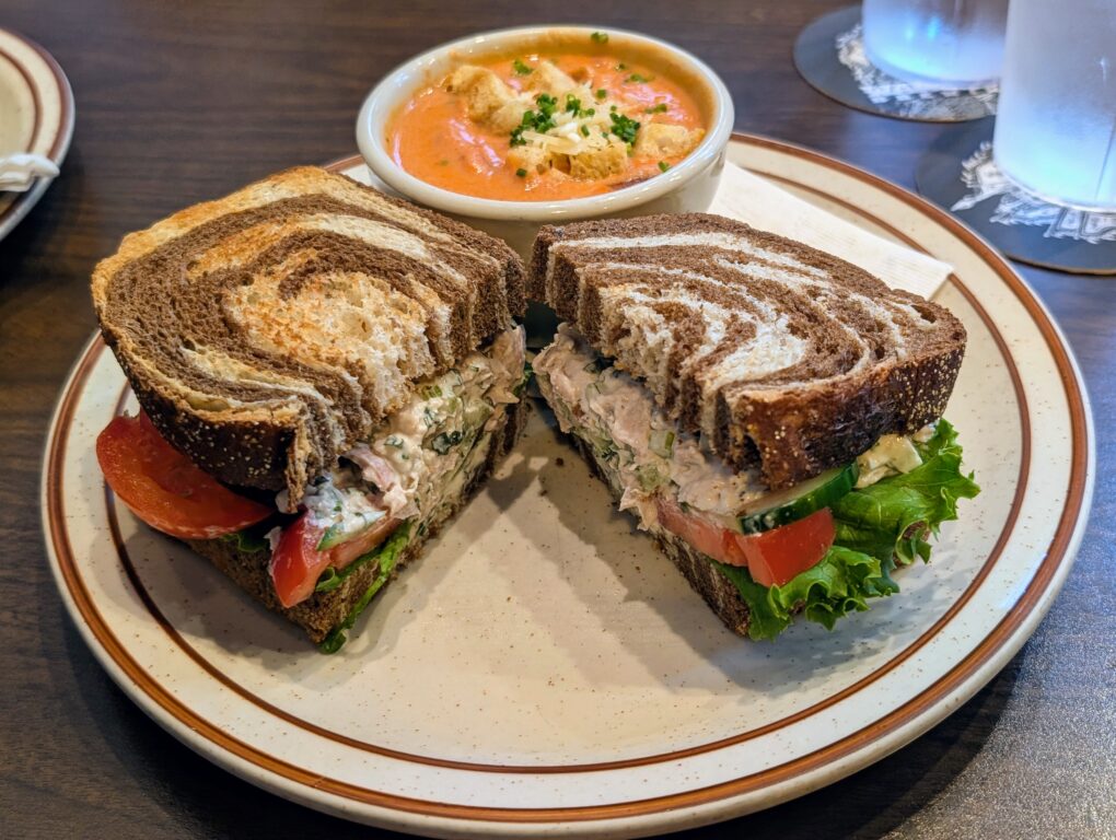 Chicken salad sandwich on swirled rye bread and tomato soup