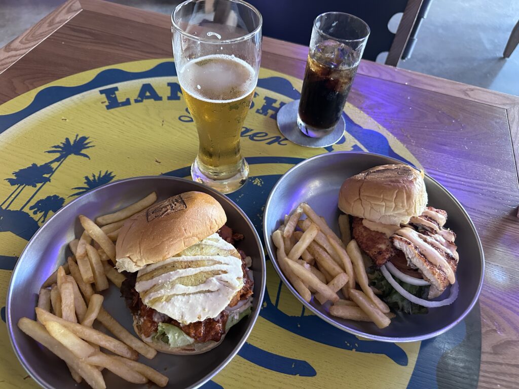 Two sandwiches, a beer and soda on a table at the Landshark Brewery at Margaritaville Island Reserve Riviera Maya
