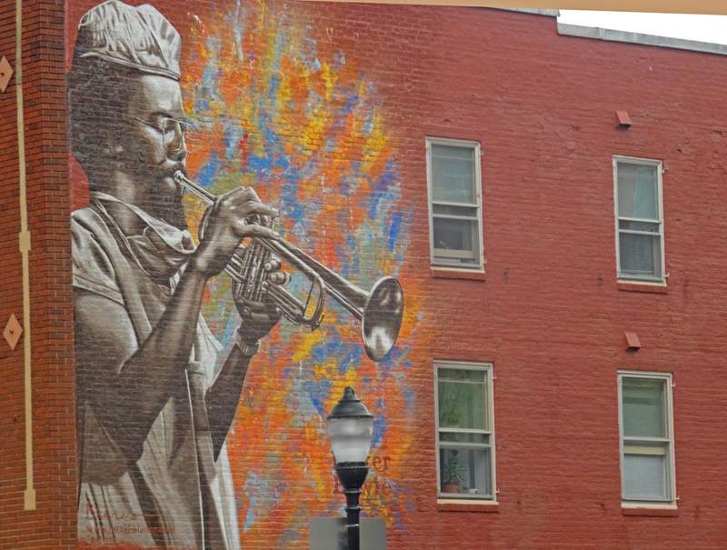 A mural of a man playing a saxaphone painted on a tall brick building