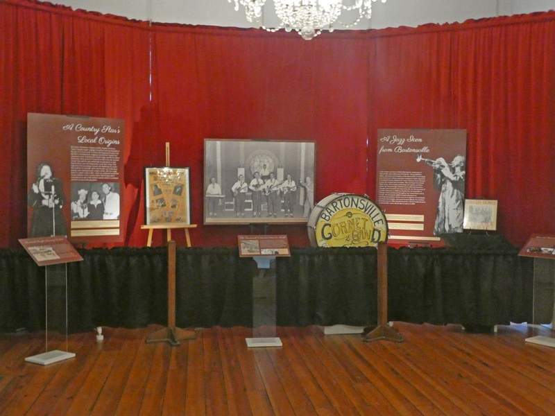An exhibit with placards and musical instruments against a red curtain background.