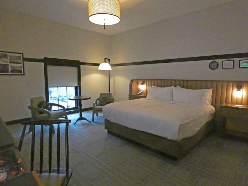 A hotel bedroom with bed and shirs and table.
