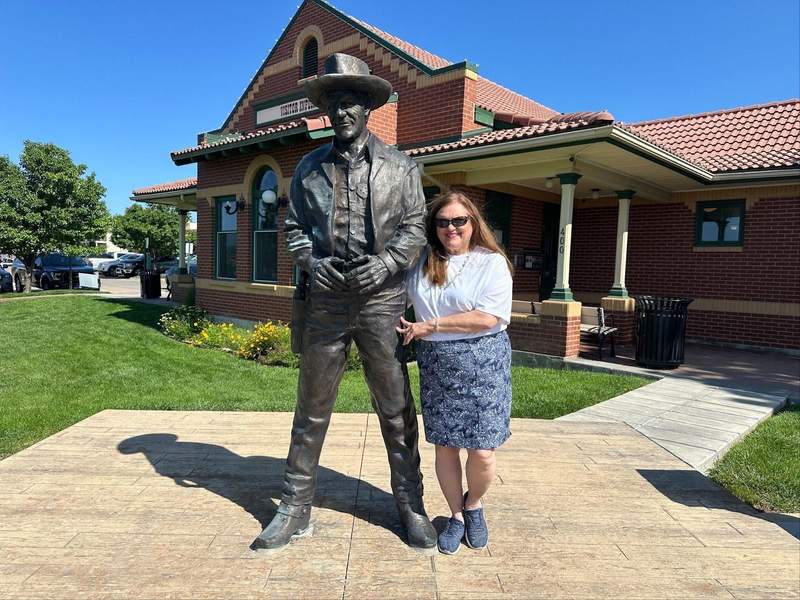 A woman standing beside the Matt Dillon statue, a stop on the Kansas Gunsmoke Trail