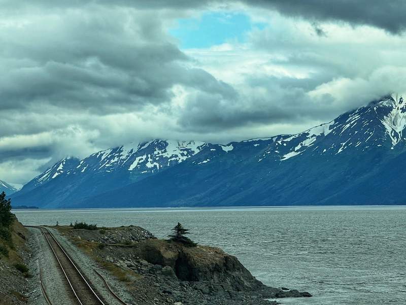Railroad track next to water with mountains in the background