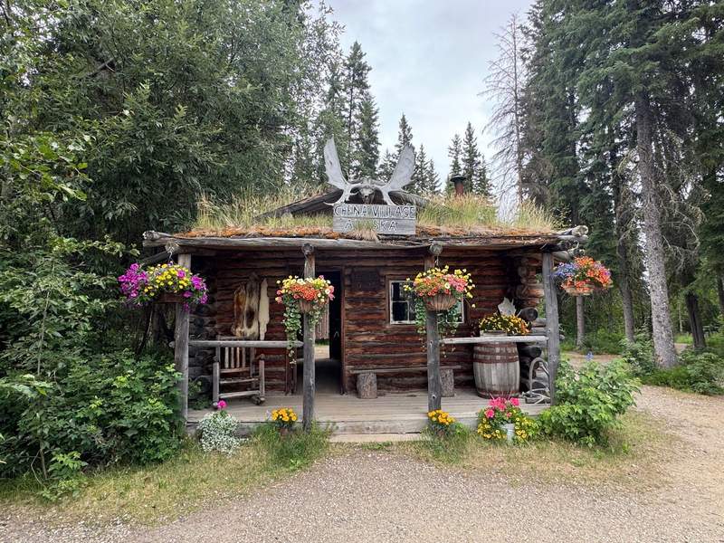Wood cabin with flowering plants and a grass top roof