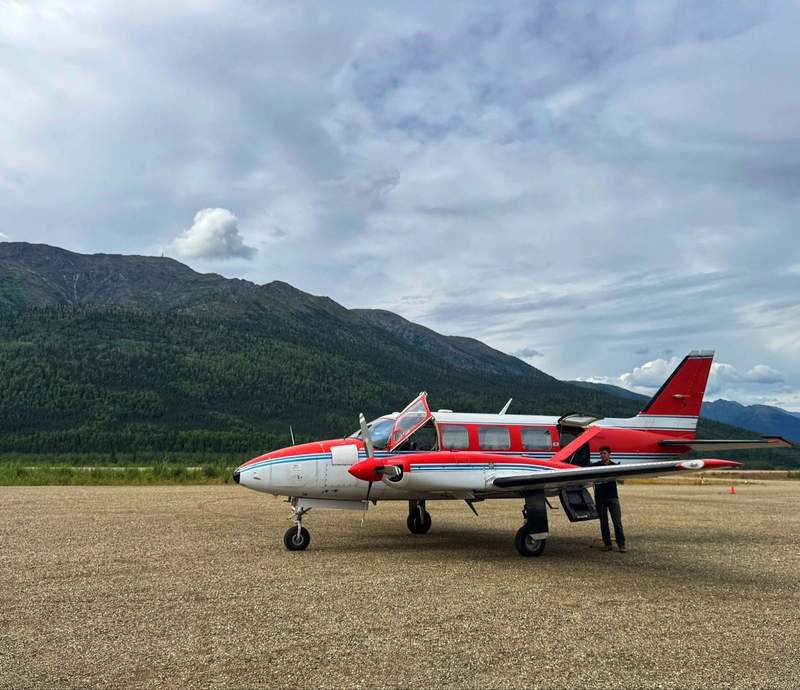 Small plane on a dirt runway with mountains in the background