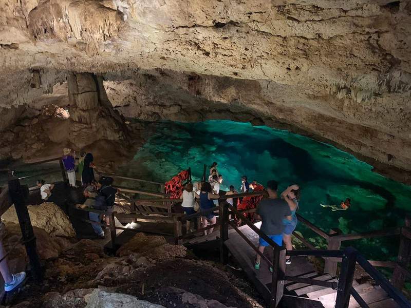 People getting ready to swim at an underground limestone cave filled with clear-blue water.