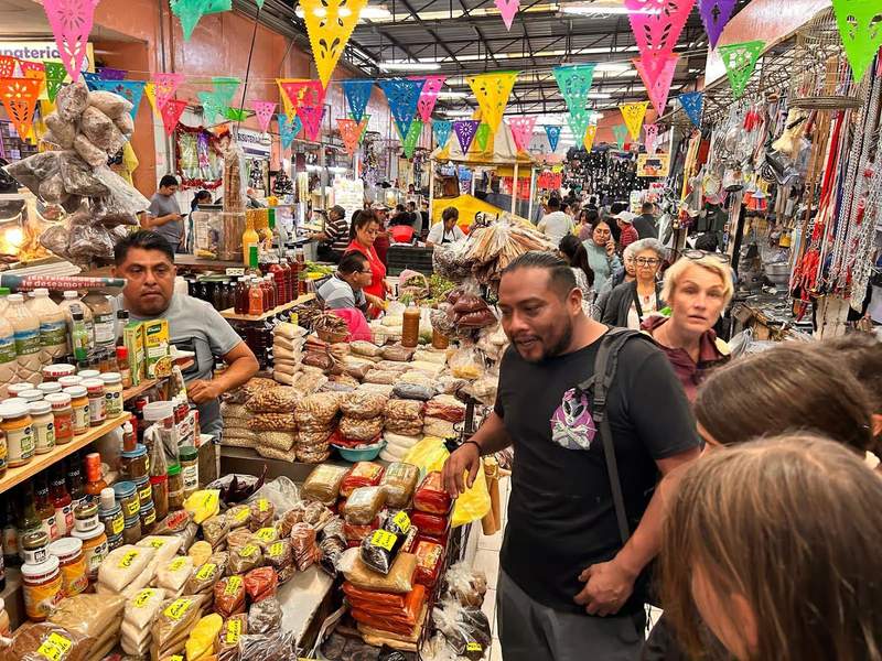 Man leading a group of people through a traditional Mexican market.
