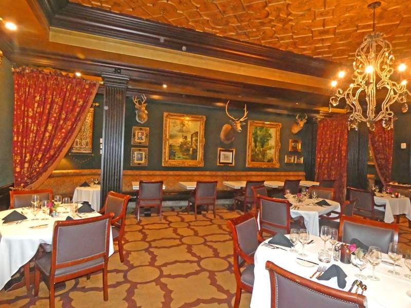  A upscale dining room with paintings on the wall and drapes.