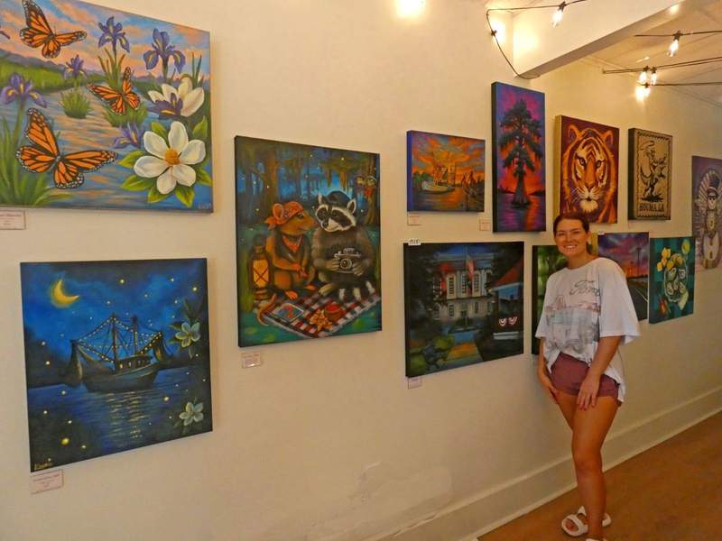 Woman standing in front of a wall of paintings.