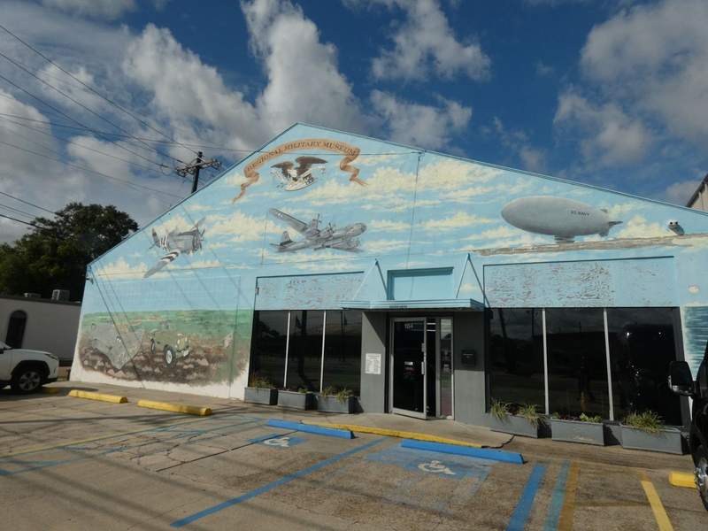Regional Military Museum with a mural depicting planes and a blimp in the sky and a jeep and tank on the ground painted on front.