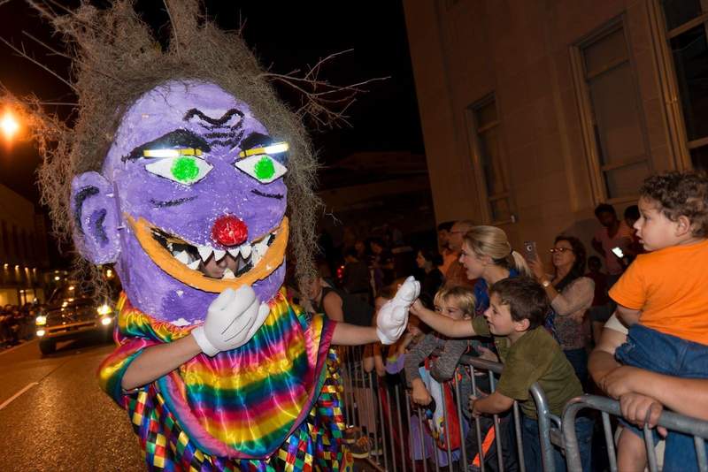 Brightly costumed character in parade interacts with spectators.