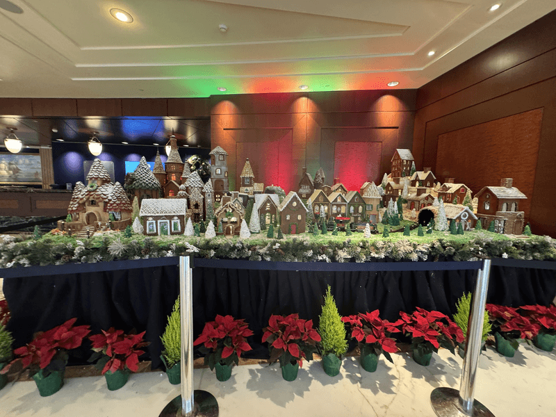 A gingerbread house village with red and green plants in the foreground. 