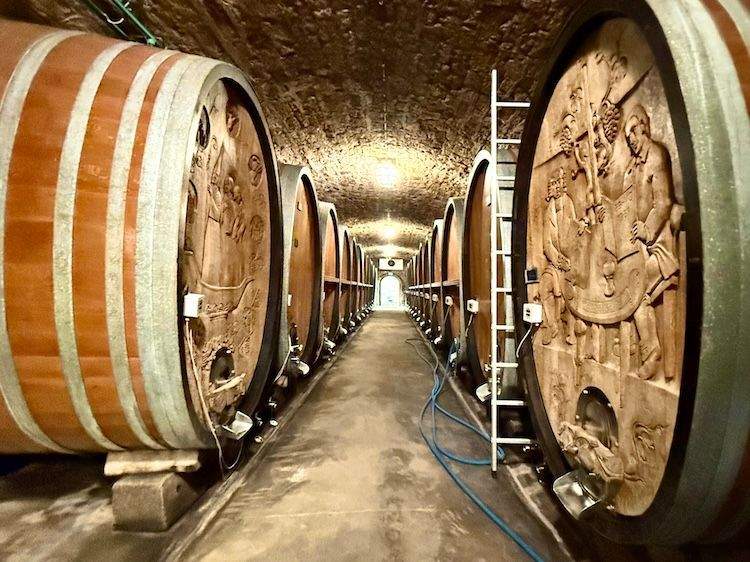 Interior of the Bürgerspital zum Heiligen Geist wine cellar in Würzburg, showing massive carved wooden casks and vaulted ceilings.