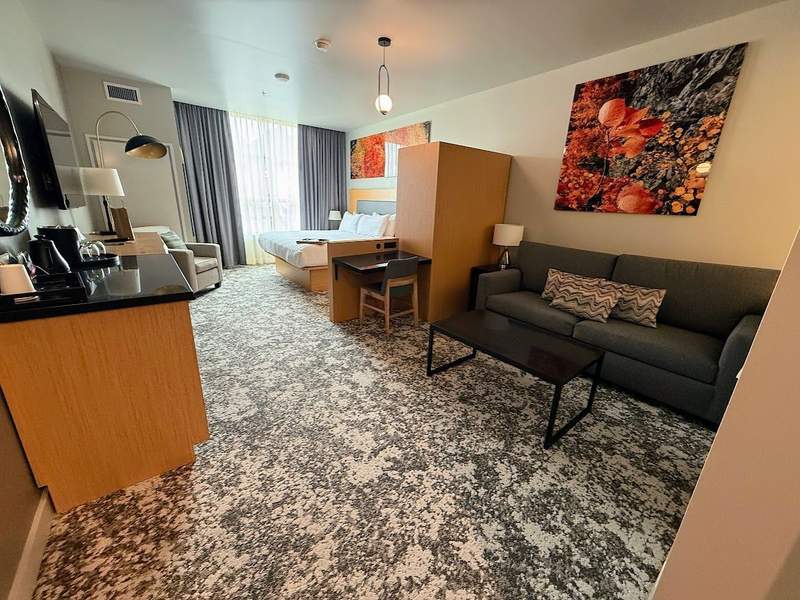 A suite style room at The Springs Resort in Pagosa Springs, Colorado, features a king size bed, a sitting area and large windows.