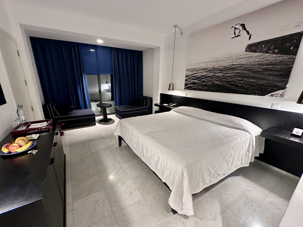 Almyra king room with large black and white painting and two navy lounge chairs in Paphos, Cyprus