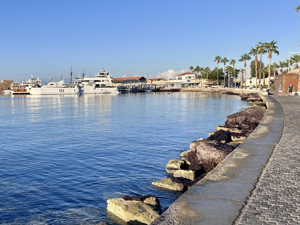 Paphos harbor in Cyprus with yachts and a walking path.