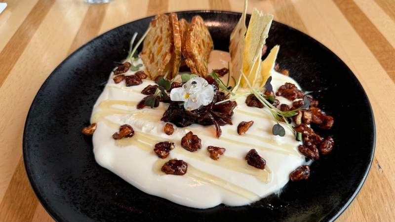 whipped ricotta on a black plate covered in nuts and bread at The Dean. 