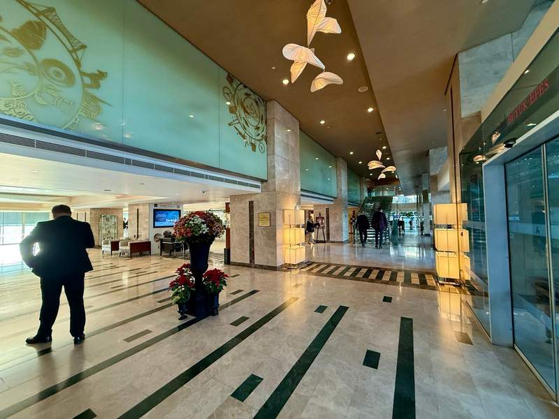 A man checking his phone in the the elegant Swiss Hotel Izmir lobby.