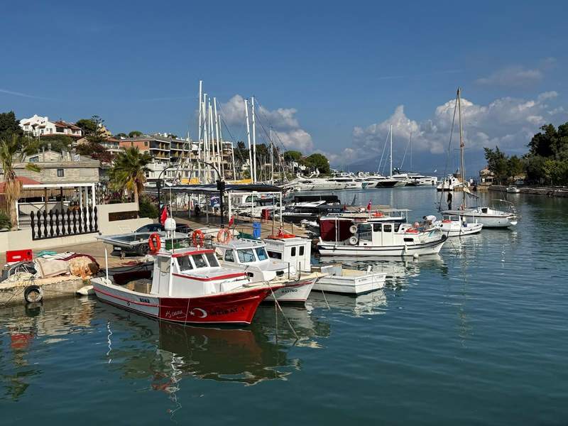 a harbor shoreline with colorful boats moored against the dock at Çeşme Harbor in Izmir.