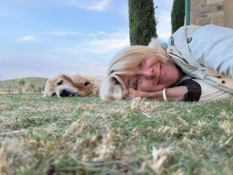 Author lying down next to a sleeping golden retriever on grass at Urla Winery.