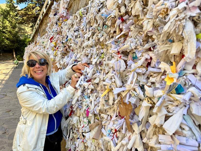 Author tucking a small note into the wish wall, a wall covered in small notes tucked into the cracks and crannies of wall at the House of the Virgin Mary.