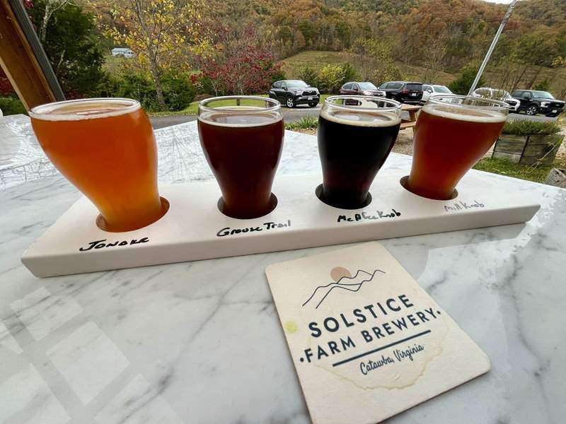 Four small glasses of beer on outside table with Virginia's Blue Ridge Mountains in the background. 
