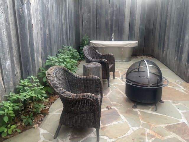 The front patio of the tent has chairs, a soaking tub and a fire pit.